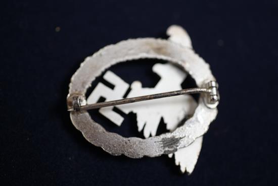 A collection of various German Third Reich cap badges, cloth badges and pins